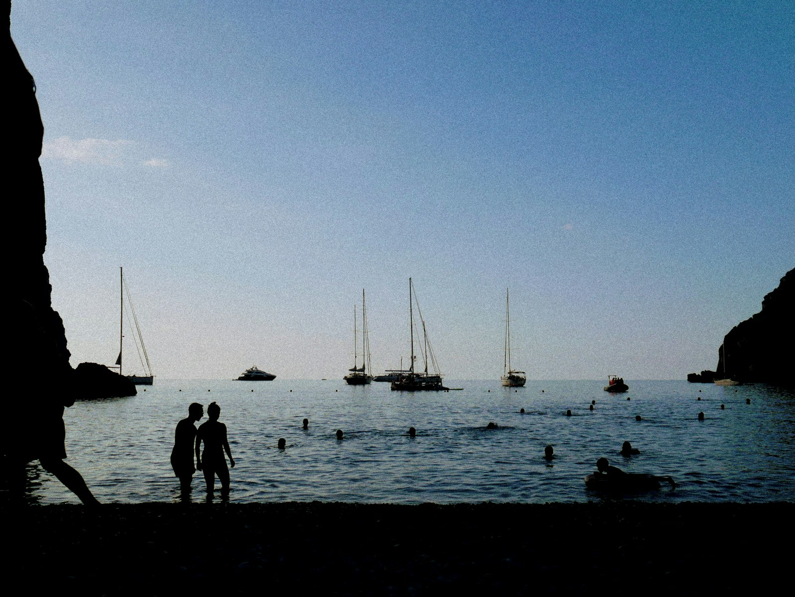 A couple of people standing next to a body of water